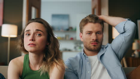 Worried-pair-watching-movie-living-room-zoom-on.-Nervous-couple-empathizing-film