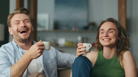 Laughing-lovers-coffee-cups-holding-at-home-closeup.-Carefree-spouses-having-fun