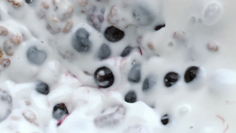 Granola-berries-mixing-process-top-view.-Cereal-muesli-floating-calcium-milk