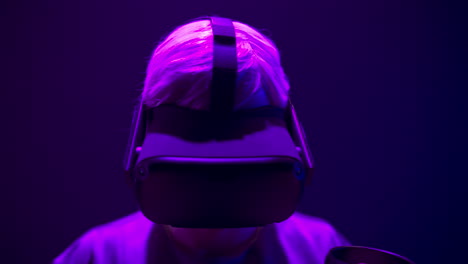 Guy-helmet-enjoying-3d-movie-in-neon-light-closeup.-Focused-man-watching-headset