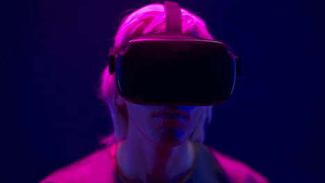 Focused-man-watching-VR-headset-in-neon-light-closeup.-Guy-enjoying-3d-movie