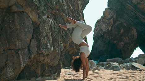 Young-woman-headstand-exercising-beach-vertical.-Girl-practicing-yoga-on-nature.