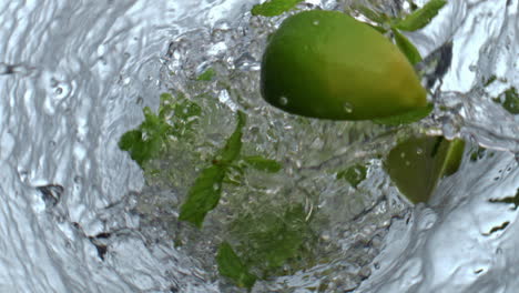 Lime-mint-falling-water-glass-top-view.-Fresh-citrus-slices-throwing-in-drink