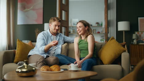 Happy-pair-chatting-having-breakfast-at-home.-Emotional-man-telling-funny-story