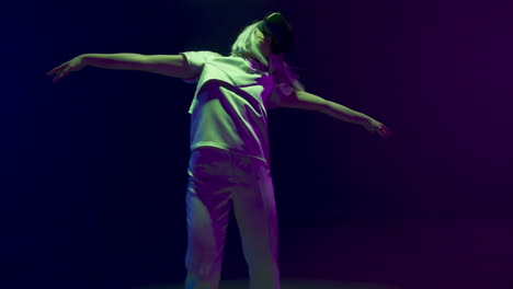 Neon-gamer-dancing-headset-in-dark-cyberspace.-Futuristic-woman-enjoying-vr