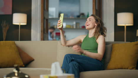 Carefree-woman-making-selfie-holding-phone-at-home.-Girl-enjoying-new-face-app