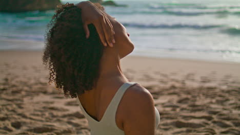 African-girl-stretching-neck-on-sand-beach-close-up.-Woman-warm-up-at-sunrise.