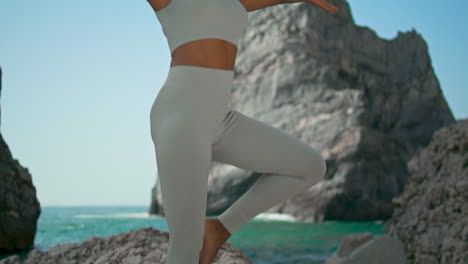 Girl-practicing-asana-tree-standing-rocky-Ursa-beach-vertically.-Woman-yoga-pose