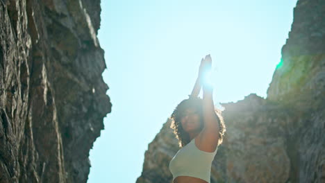 Yogi-woman-hands-up-standing-in-front-bright-sunlight-close-up.-Girl-stretching.