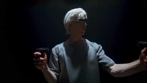 Teenager-playing-augmented-reality-game-in-dark-room.-Focused-blonde-man-using