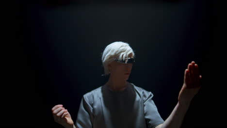 Man-using-vr-headset-touch-invisible-objects-in-dark-room.-Blonde-guy-experience