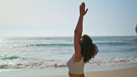 Yogi-girl-standing-sand-near-ocean-waves-making-Namaste-hands.-Woman-meditating.