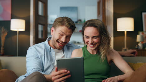 Laughing-lovers-watching-tablet-comedy-at-home-closeup.-Two-people-having-fun