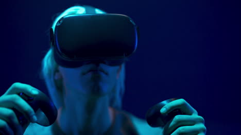 Beeindruckter-Mann,-Der-VR-Headset-Videospiel-Neonhintergrund-Erlebt.-Zukunftskonzept