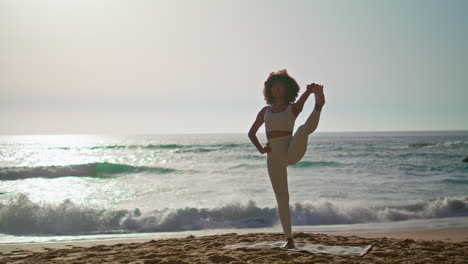 Woman-practicing-pose-balance-on-beach-at-sunrise.-Girl-standing-on-one-leg.