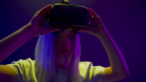 Shocked-gamer-raising-headset-room.-Woman-taking-off-virtual-reality-glasses
