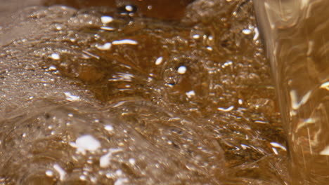 Fizzy-cider-foaming-vessel-closeup.-Carbonated-ale-swirling-establishing-view