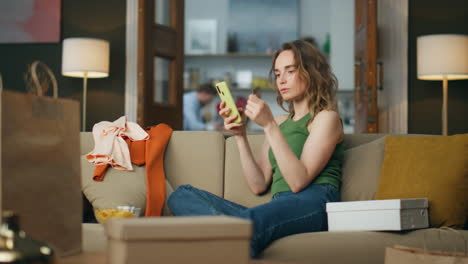 Involved-woman-shopping-cellphone-at-home.-Young-customer-paying-credit-card