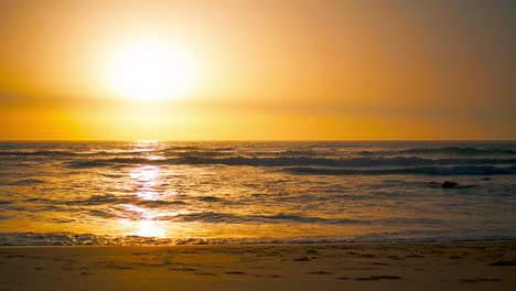 Sonnenaufgangslandschaft-Am-Ursa-Beach-Mit-Orangefarbener-Sonne,-Die-Die-Oberfläche-Des-Atlantiks-Reflektiert