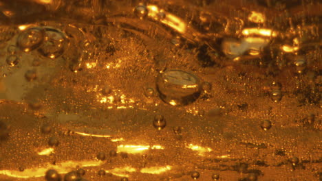 Splashes-light-beer-glass-closeup.-Golden-carbonated-beverage-swashing-waving