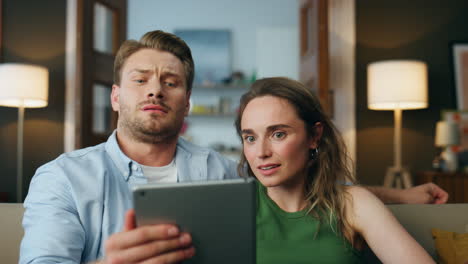 Shocked-couple-staring-pad-digital-device-home-closeup.-Spouses-examining-tablet
