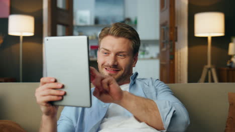 Excited-guy-achieving-pad-computer-at-house-zoom-on.-Satisfied-man-saying-wow
