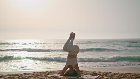 Girl-practicing-lotus-headstand-at-sunrise-Ursa-beach.-Lady-exercising-outdoor
