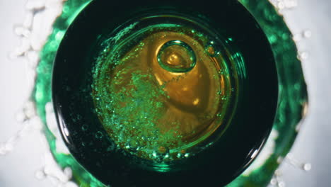 Ice-cube-falling-container-closeup.-Golden-ale-splashing-from-flask-slow-motion