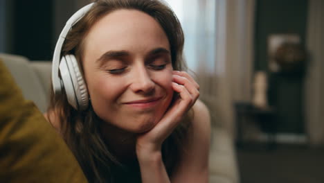 Relaxed-woman-listening-earphones-laying-home-closeup.-Happy-girl-moving-head