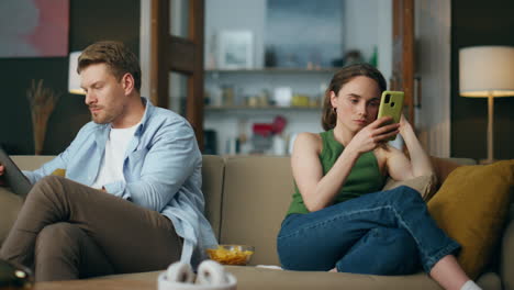 Internet-addicted-pair-gadgets-holding-at-sofa-home.-Contemporary-family-weekend