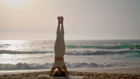 Vertikale-Kopfstand-Yoga-Pose-Einer-Frau-Am-Meeresufer-Bei-Sonnenaufgang.-Mädchen-Trainiert-Gleichgewicht