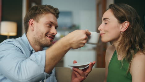 Gentle-man-treating-wife-coffee-cup-at-couch-closeup.-Couple-drinking-espresso