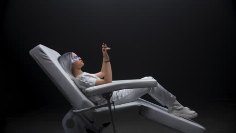 Gamer-getting-AI-experience-dark-room.-Haptic-gloves-woman-sitting-armchair