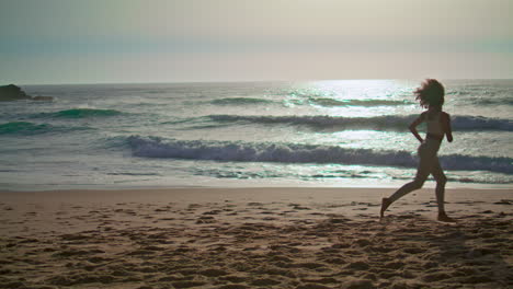 Energetic-woman-jogging-beach-sunrise-vertical-shot.-Happy-girl-spinning-coast