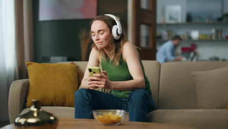 Relaxed-girl-listening-headphones-music-sofa-interior.-Lady-moving-in-song-beat
