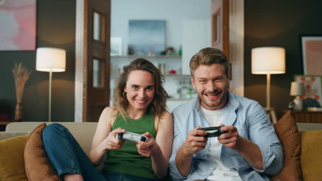 Überglückliche-Freunde-Genießen-Videospiele-Zu-Hause.-Unbeschwertes-Paar-Hält-Gamepads