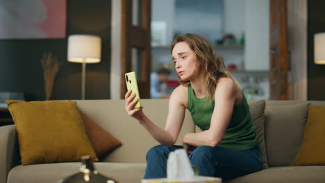 Crying-lady-talking-smartphone-on-home-sofa.-Unhappy-girl-cellphone-video-call
