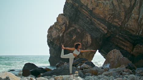 Woman-practicing-pose-dancer-on-rocky-seacoast.-Girl-training-balance-on-nature.