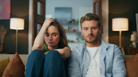 Sad-family-sitting-sofa-at-living-room-zoom-out.-Unhappy-couple-after-quarrel