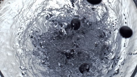 Berries-tossing-whirlpool-water-glassware-top-view.-Air-bubbles-cocktail-moving