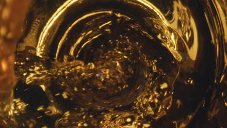 Golden-liquid-flowing-goblet-closeup.-Golden-lager-beer-waving-inside-glassware