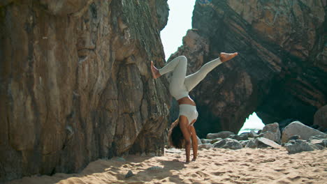 Woman-standing-hands-practicing-yoga-on-sand-seashore.-Girl-training-strength.
