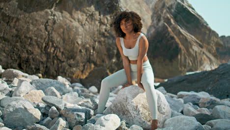 Woman-training-yoga-firefly-pose-on-big-stone-seacoast.-Girl-training-balance.