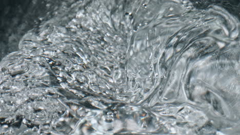 Closeup-bubbling-aqua-texture.-Cold-water-swirling-inside-glassware-top-view