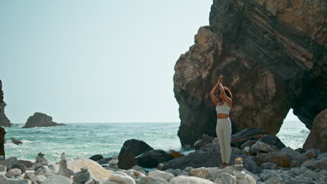 Girl-exercising-raising-hands-sky-on-seashore-vertical.-Woman-meditation-beach