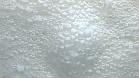 Foamy-lactose-drink-surface-top-view.-Milk-liquid-frothing-texture-closeup