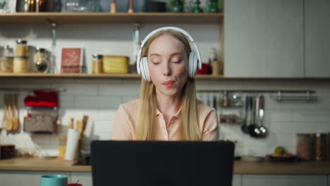 Online-Student-Hört-In-Der-Küche-Mit-Kopfhörern-Musik-Und-Hat-Einen-Laptop-In-Nahaufnahme.