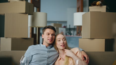 New-homeowners-sitting-couch-in-room-with-boxes-close-up.-Family-relocation.