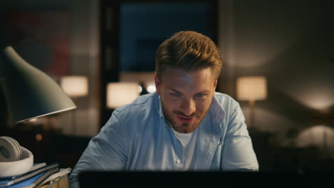 Laughing-guy-chatting-computer-cozy-apartments-closeup.-Person-reacting-on-joke
