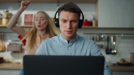 Manager-Berät-Online-Webcam-Mit-Kopfhörern-In-Der-Küche,-Während-Frau-Tanzt